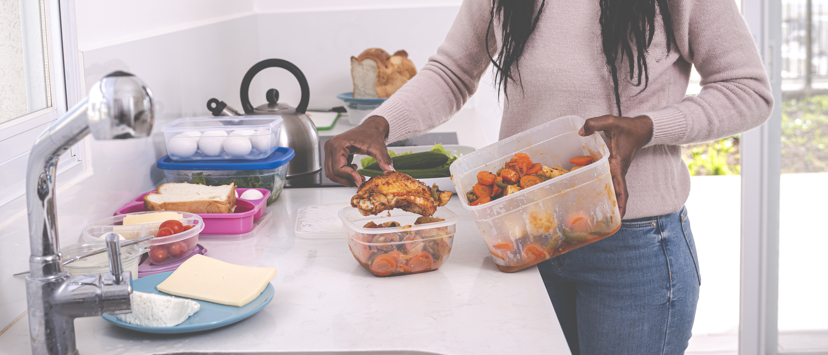 Woman packing leftovers into plastic containers on kitchen counter
