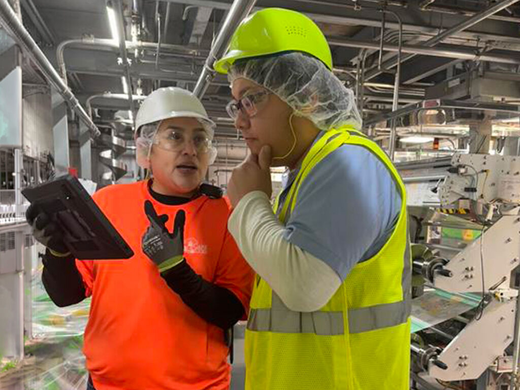 Employee training a colleague on a program at a supply chain facility.