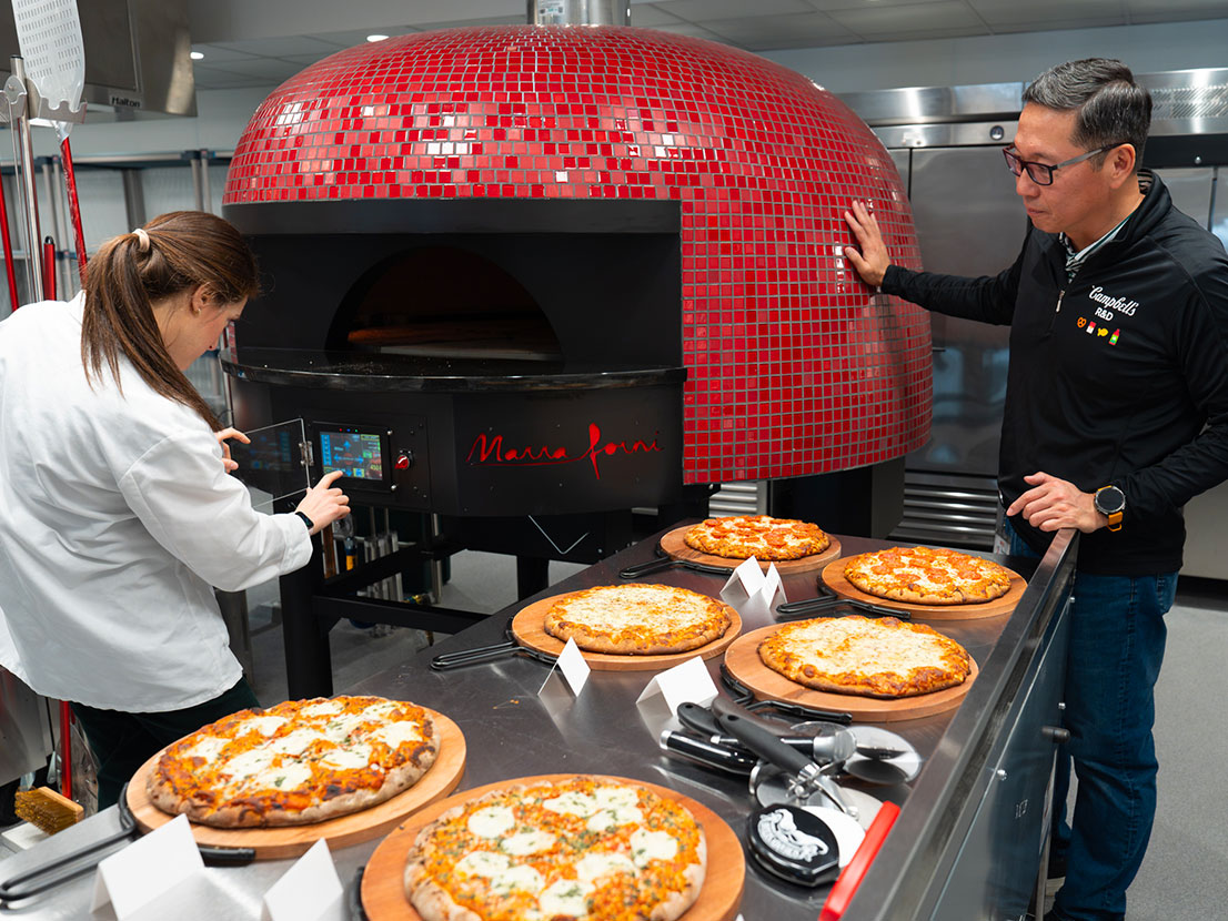 R&D team cooking pizza in brick oven